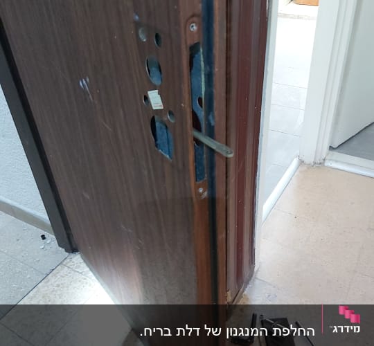 דלת פתוחה עם מנעול מפורק וכלי עבודה על הרצפה